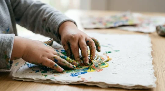 Close-up of a child's hands engaged in creative art-making, emphasizing process over product in emotional regulation