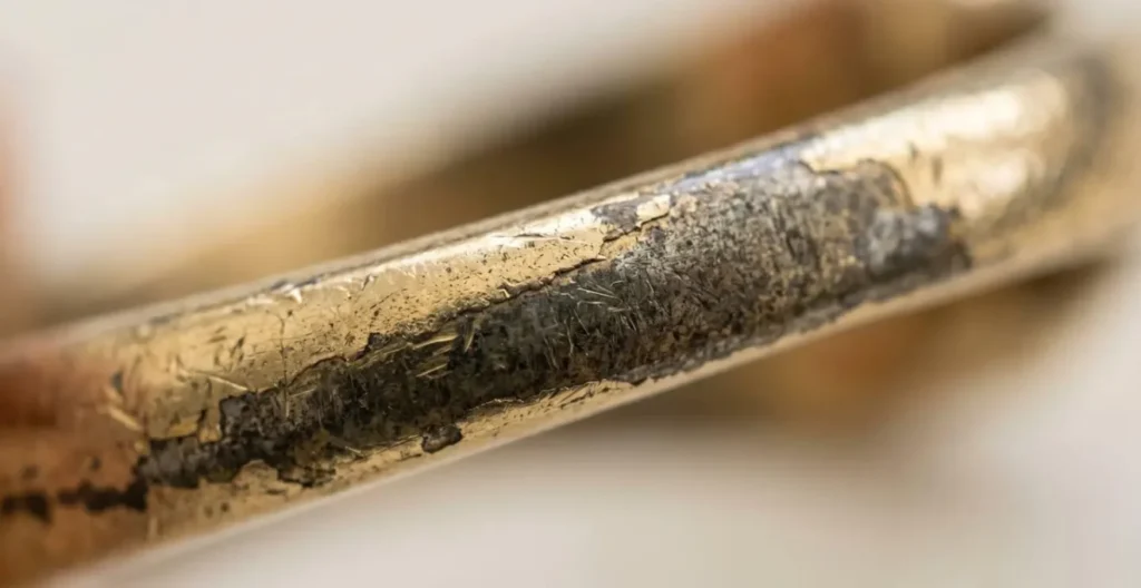 Extreme macro view of metal surface showing worn coating revealing base metal underneath Extreme macro view of metal surface showing worn coating revealing base metal underneath
